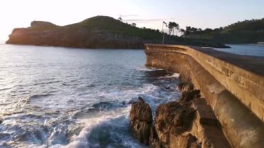 Bir yaz günü gün doğumunda Lekeitio iskelesinde dalgalar kopuyor.