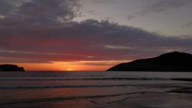 Kumsalda bulutlu gün batımı. Yüksek renk karşıtlığı