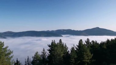 Alçak bulutlarla kaplı vadinin manzarası ve arka planda dağ zirveleri