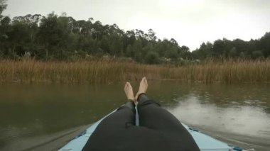 Neoprenli giyinmiş çocuk bulutlu bir öğleden sonra bitki örtüsünde yelken açıyor.