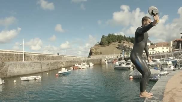 天気の良い朝 桟橋から水の中にSomersaultジャンプしている間 ウェットスーツの少年は 自撮りモードで自分自身を記録 — ストック動画