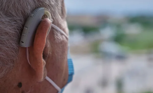 close-up of older man face with headphones and mask