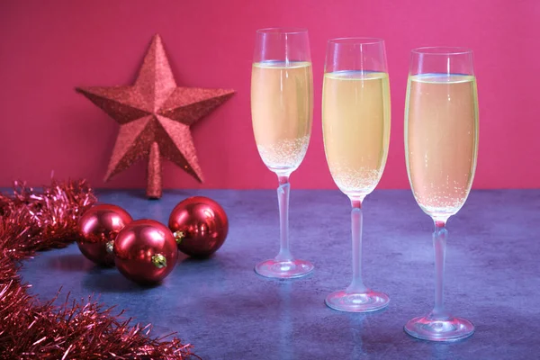 Christmas scene with three champagne glasses filled with red sparkling wine and bright red star