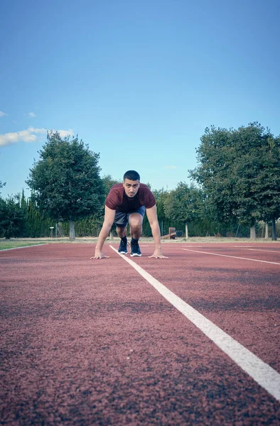 Front view with blue sky background of an athlete starting his career on a track