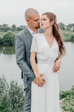 Gelin ve damat gölün arka planında kucaklaşıyor.
