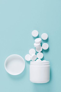 Hap hap şişesi üzerinde mavi arka plan, üstten görünüm dışarı dökülmesini