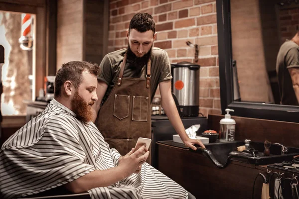 Barber and bearded man in barber shop — Stock Photo, Image