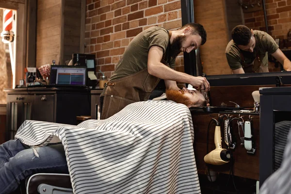 Barber and bearded man in barber shop — Stock Photo, Image