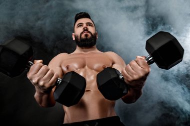 kaslı adam dumbbells ile yapıyor.