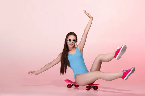 Femme avec skateboard sur fond rose — Photo