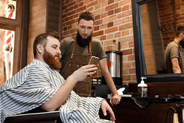 Barber and bearded man in barber shop — Stock Photo, Image