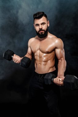 atletik kaslı adam dumbbells ile yapıyor.