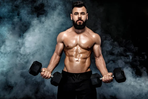 Atletik kaslı adam dumbbells ile yapıyor. — Stok fotoğraf