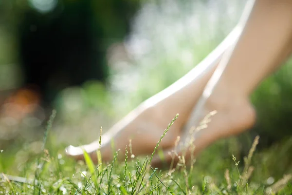 Jambes féminines marchant sur l'herbe verte — Photo