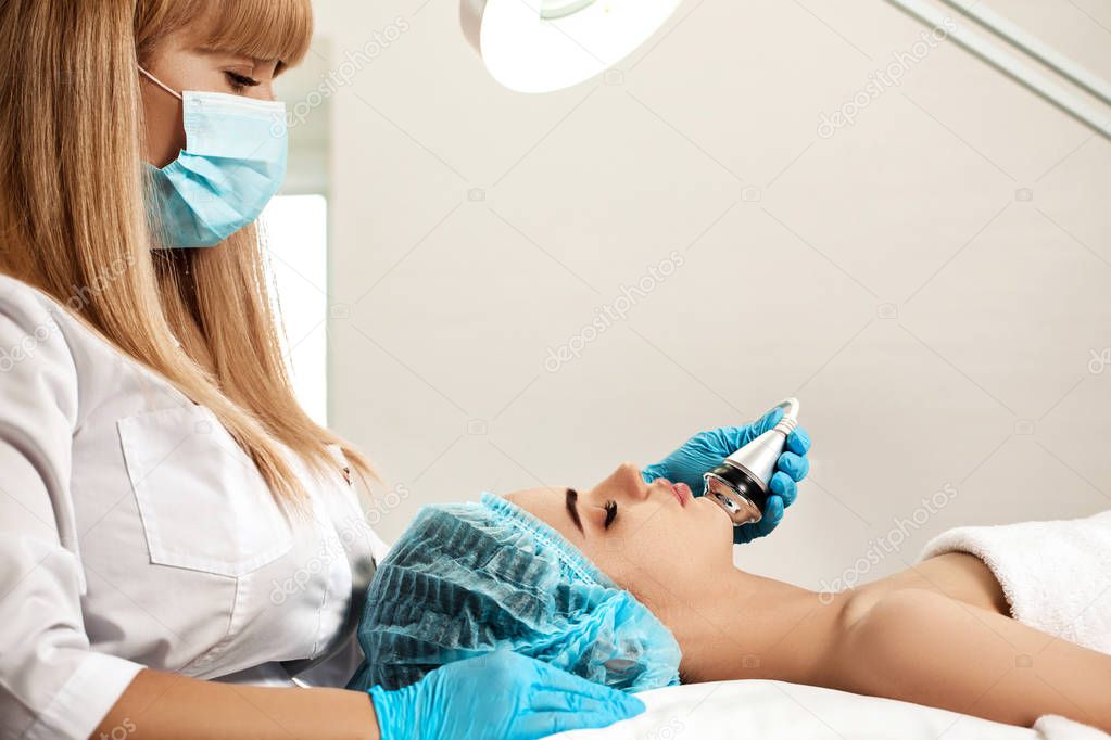 Beautician makes cleaning of face in spa salon.