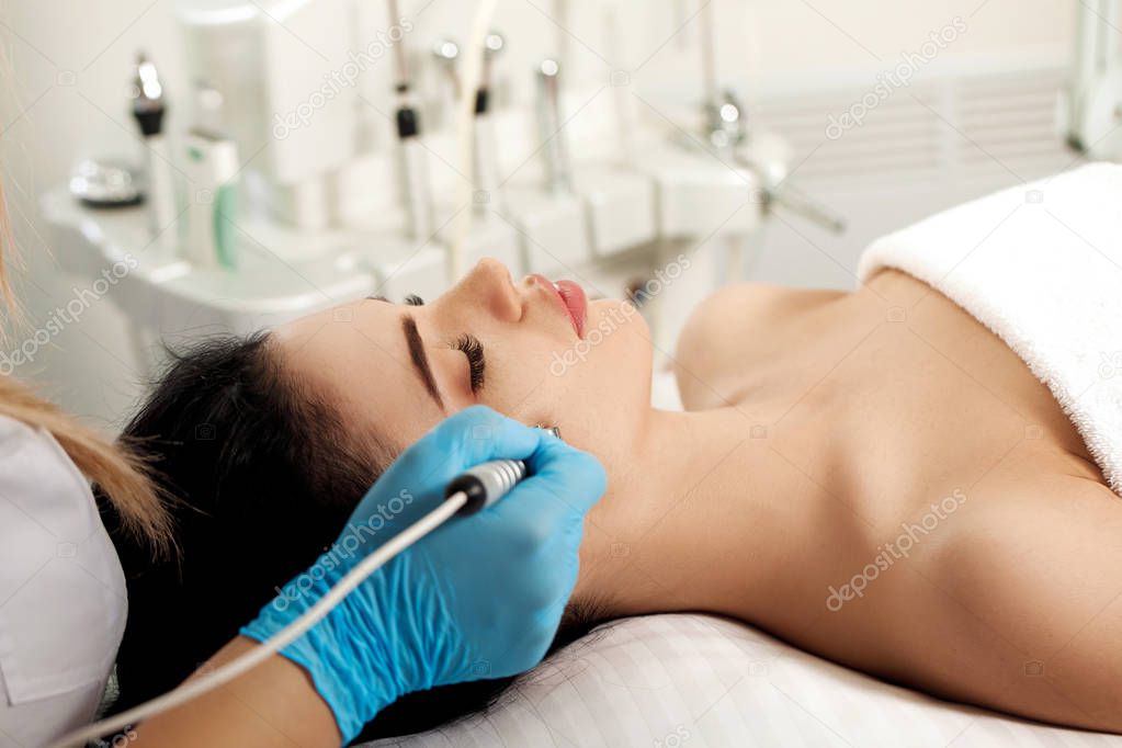 Beautician makes cleaning of face in spa salon.