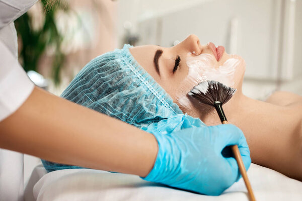 beautician applies face mask on woman