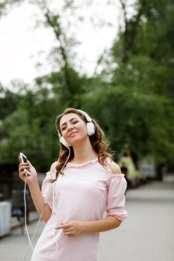Genç bir kadın kulaklıkla müzik dinliyor.