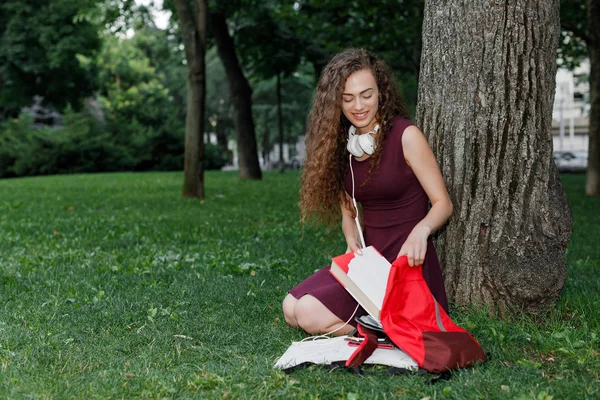 Chica estudiante sosteniendo libro y sentado bajo árbol — Foto de Stock