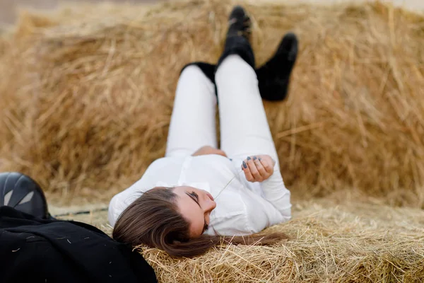 干し草に鞭で仮面ライダーの女性が座っています。 — ストック写真