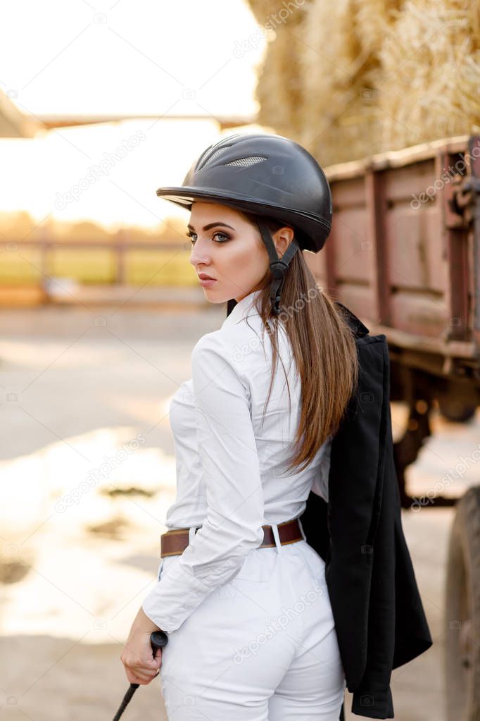 rider woman in helmet stands near stables