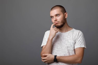 Gri arka plan üzerinde hayal kırıklığına uğramış genç adam portresi. üzüntü