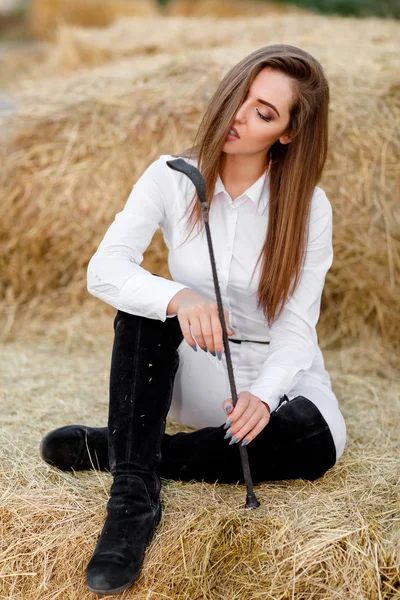 Reiterin mit Peitsche sitzt auf Heu — Stockfoto