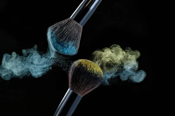 Make up brush with powder splashes on black background