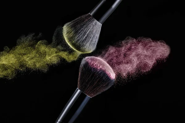 Make up brush with powder splashes on black background