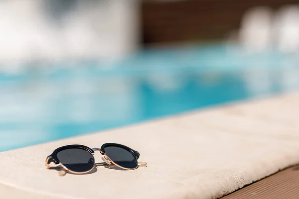 Gafas de sol junto a la piscina en un soleado día de verano . —  Fotos de Stock