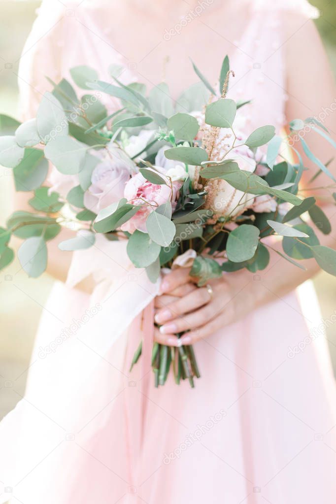 brides hands hold a beautiful bridal bouquet outdoor