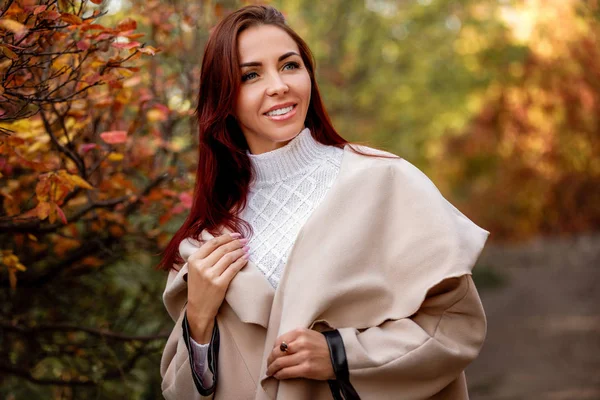 Vrouw in beige jas op een achtergrond van gele herfst bladeren — Stockfoto