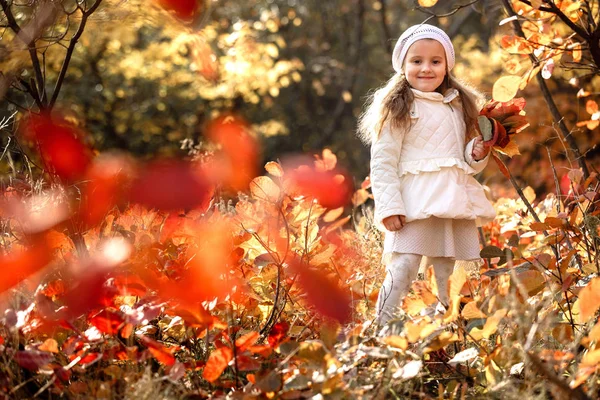 baby girl pick up a bouquet of yellow leaves on autumn day
