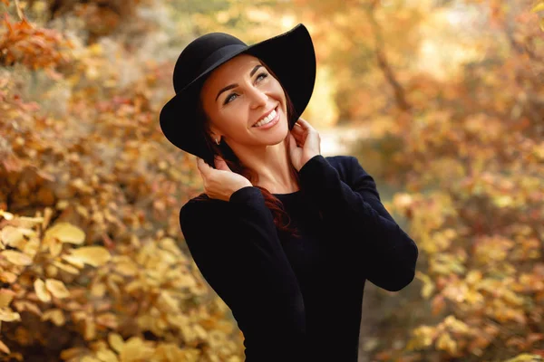 Kobieta w sukni i kapeluszu na tle jesiennych liści — Zdjęcie stockowe