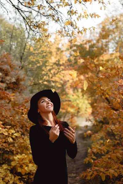 Mujer en vestido y sombrero en el fondo del follaje de otoño — Foto de Stock