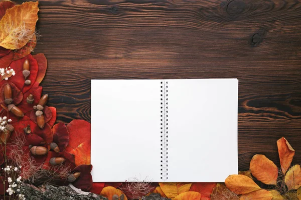 Podzimní listí, cukroví a papírového poznámkového bloku na dřevěné pozadí — Stock fotografie