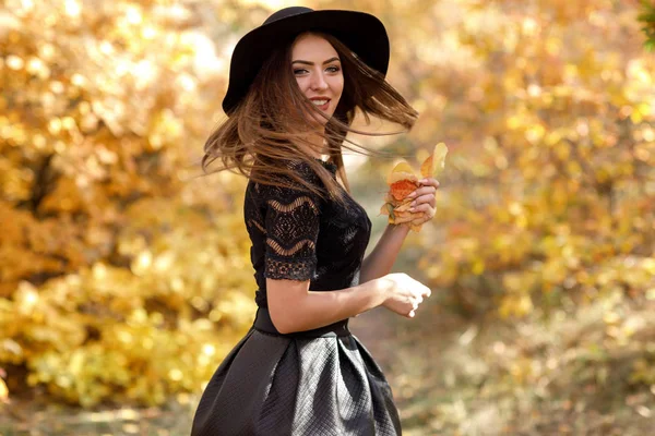 Bela mulher em vestido preto e chapéu no outono — Fotografia de Stock