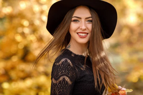 Bela mulher em vestido preto e chapéu no outono — Fotografia de Stock