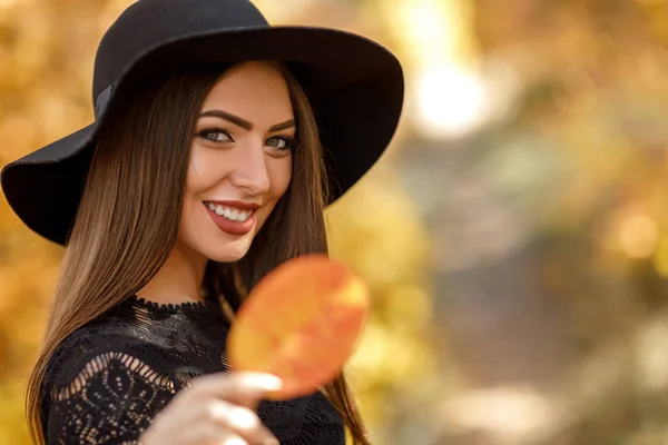 Hermosa mujer en vestido negro y sombrero en otoño — Foto de Stock