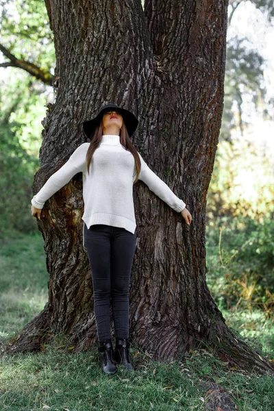 Красивая женщина в шляпе, стоящая возле большого дерева — стоковое фото