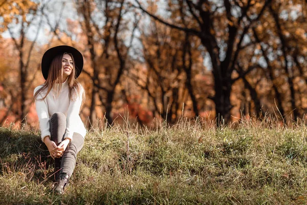 Hermosa mujer sentada en la hierba en el soleado día de otoño . — Foto de Stock