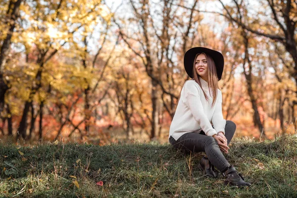美丽的女人坐在草地上阳光明媚的秋日. — 图库照片