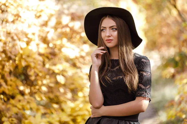 Schöne Frau in schwarzem Kleid und Hut im Herbst — Stockfoto