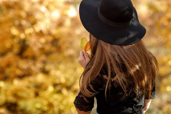 Vacker kvinna i svart klänning och hatt i höst — Stockfoto