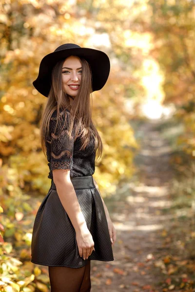 Schöne Frau in schwarzem Kleid und Hut im Herbst — Stockfoto