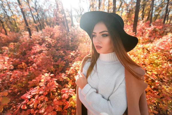 Frau mit schwarzem Hut auf dem Hintergrund der Herbstblätter. — Stockfoto