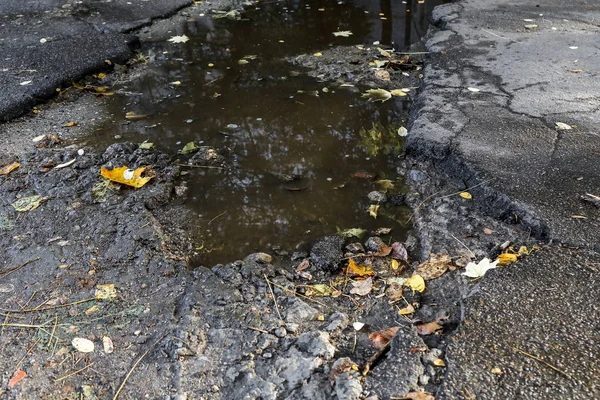 Large pit with stones on the asphalt road — Stock Photo, Image