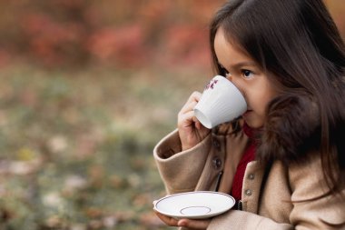 küçük kız sonbahar Park'ta sıcak çay içme