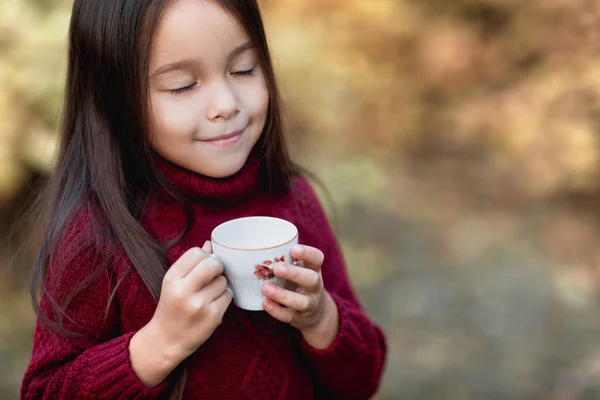 Malá holčička pití teplého čaje v podzimním parku — Stock fotografie