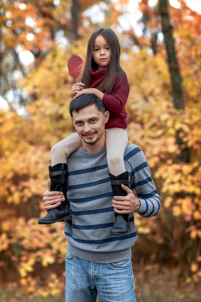 Baba küçük kızı kızla sarı yapraklar arka plan üzerinde yürür. — Stok fotoğraf